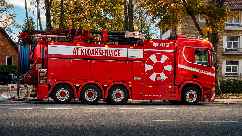 Rød slamsuger lastbil fra AT Kloakservice på gaden